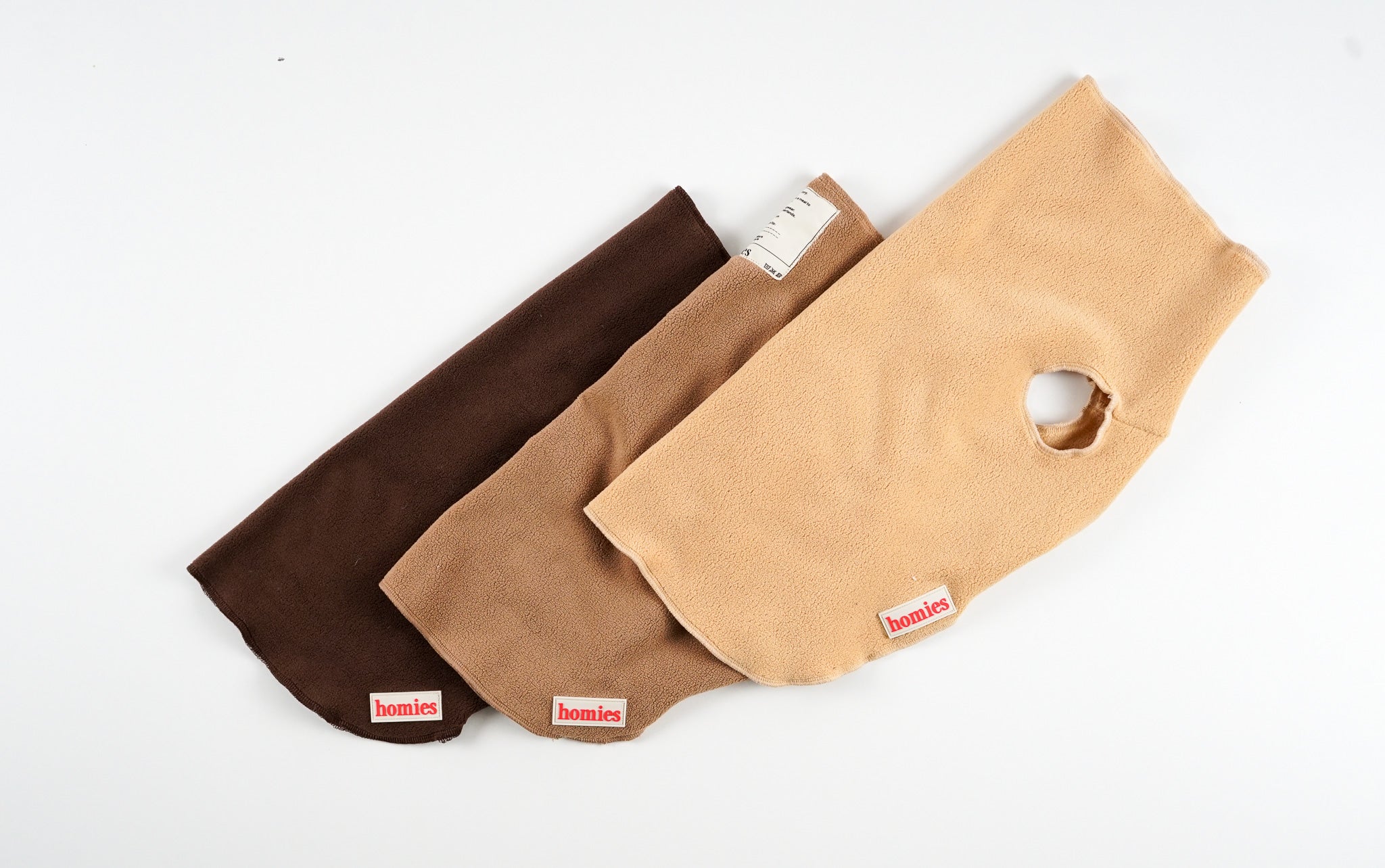 Three dog fleece sweaters in brown and beige and camel with a visible brand logo of Homies Dogwear on a white background
